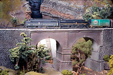 PRR FA's #9600 and #9601 lead an afternoon freight over the stone arch bridge over the Thicket River.